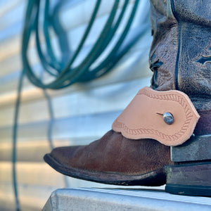 Natural Veg Tan Curve Body Spur Strap on a cowboy boot on a trailer with a rope in the background.