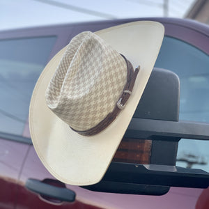 Two S Leatherwork Tenochca Hat Band on a straw hat, hanging from the mirror of a truck.