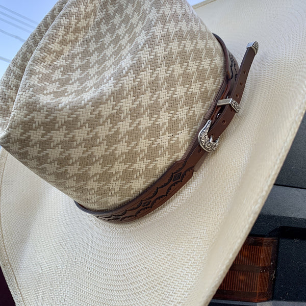 Two S Leatherwork Tenochca Hat Band on a straw hat, hanging from the mirror of a truck.